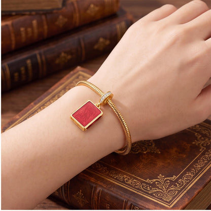 Red Book Dangle Charm close-up on a bracelet